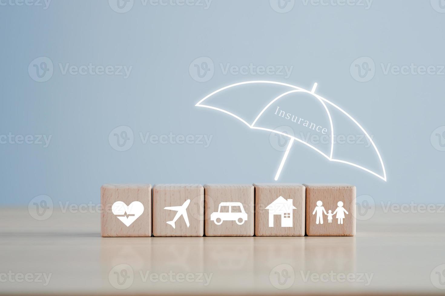 Versicherungskonzept. Schutz vor möglichen Eventualitäten. Regenschirmabdeckung Haus, Auto, Familie, Reise- und Gesundheitssymbol auf Holzblock für Lebensversicherungskonzept. foto