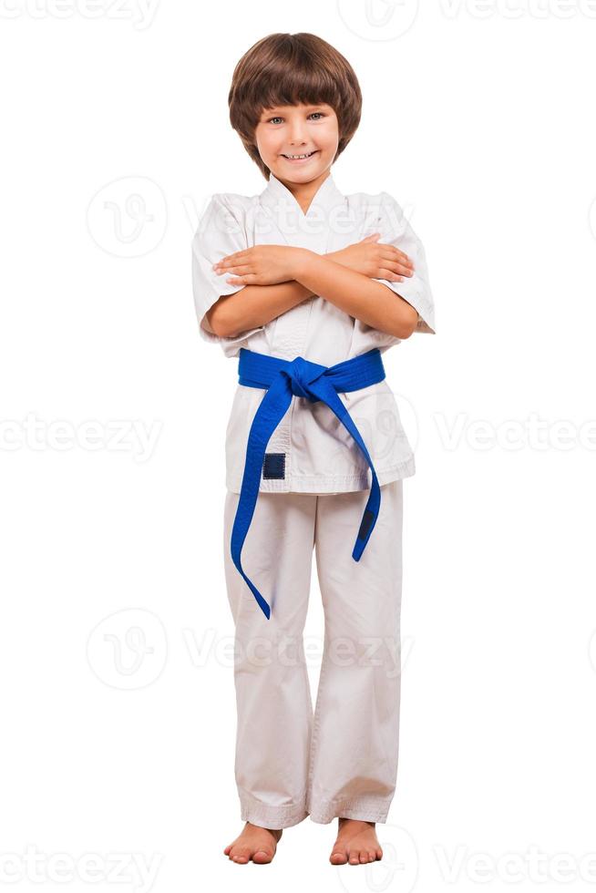 Kampfsportjunge. volle Länge des kleinen Jungen, der Karate trainiert, während er auf weißem Hintergrund isoliert ist foto