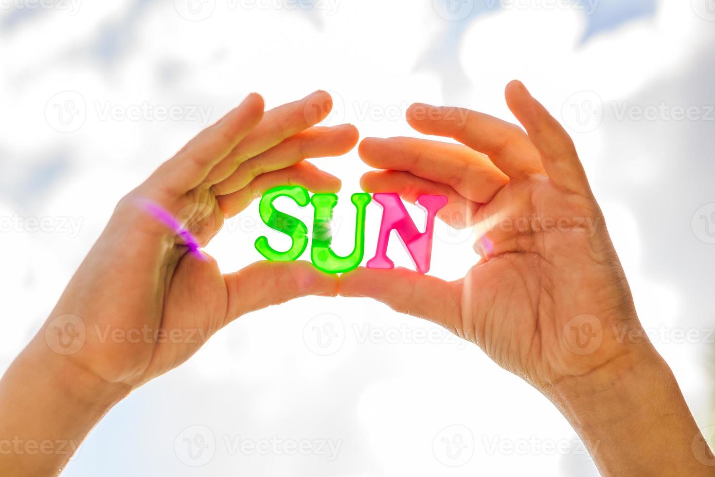 Sonne in den Händen halten. Nahaufnahme der Sonne aus Plastikbuchstaben in den Händen eines Kindes und vor dem Himmel foto