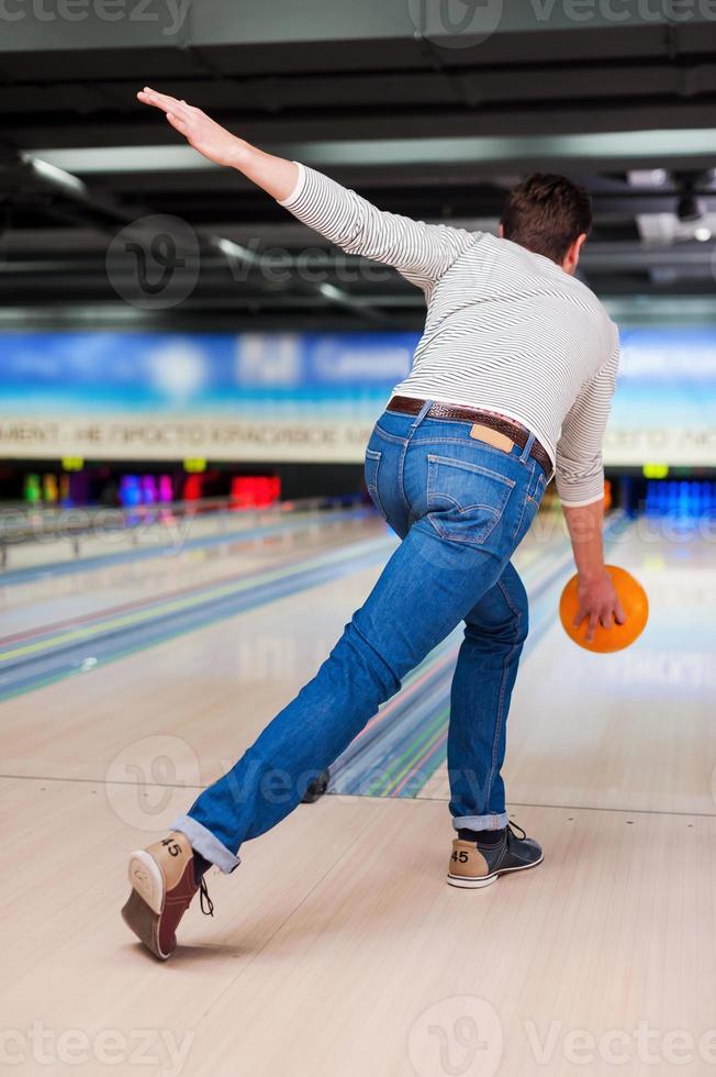 sein perfektes Spiel. Rückansicht des jungen Mannes, der Bowling spielt foto