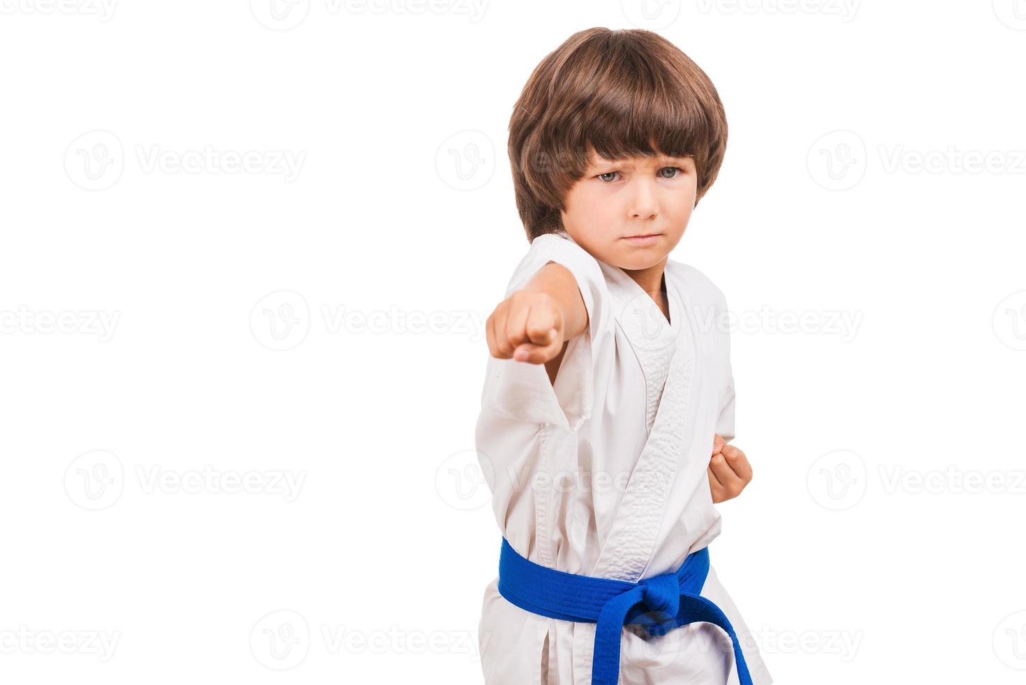 Kampfsportjunge. kleiner Junge Training Karate während isoliert auf weißem Hintergrund foto