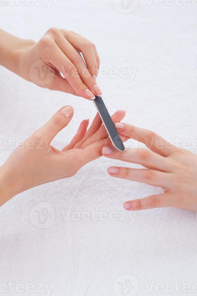 Nagelpflege. Nahaufnahme der Kosmetikerin, die die Nägel der Kundin poliert foto