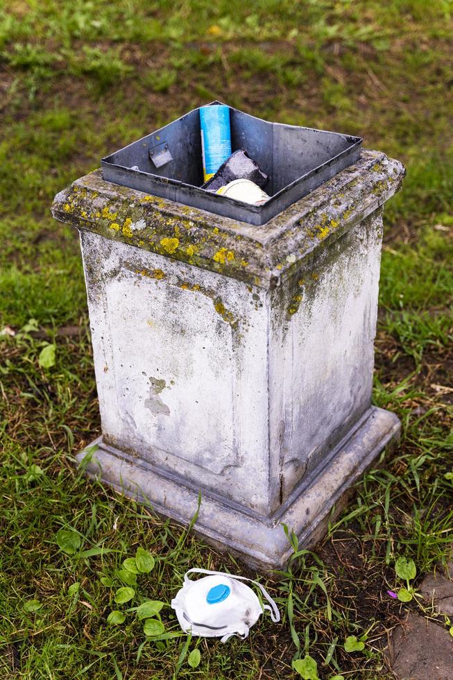 ein Abfallbehälter mit Abfall und ein weggeworfenes gebrauchtes Atemschutzgerät, Atemschutzmaske, die zum Schutz vor der Epidemie verwendet wird foto