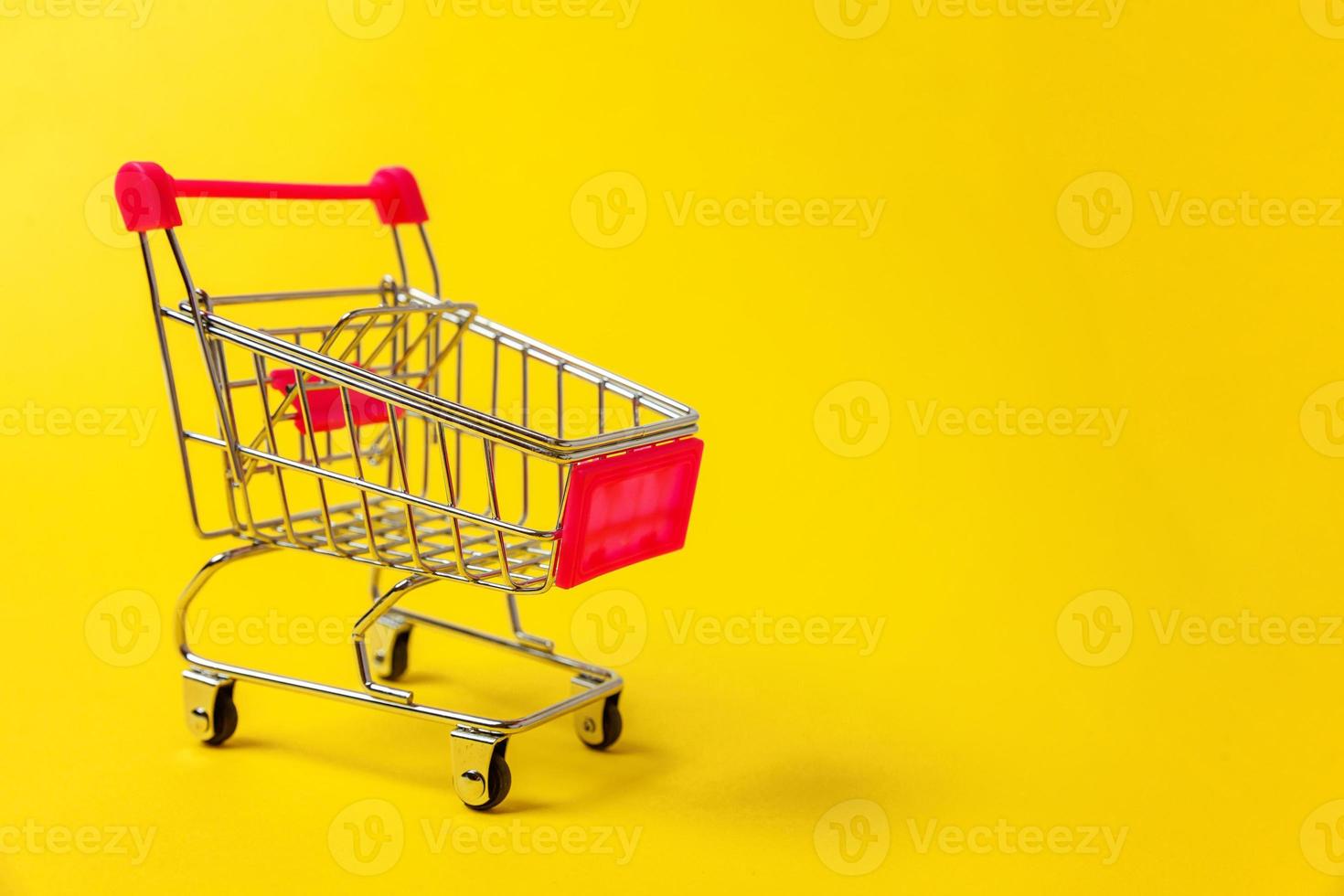 kleiner Supermarkt-Lebensmittelwagen zum Einkaufen von Spielzeug mit Rädern isoliert auf gelbem, farbenfrohem, trendigem, modernem Modehintergrund. verkauf kaufen einkaufszentrum markt shop verbraucherkonzept. Platz kopieren. foto