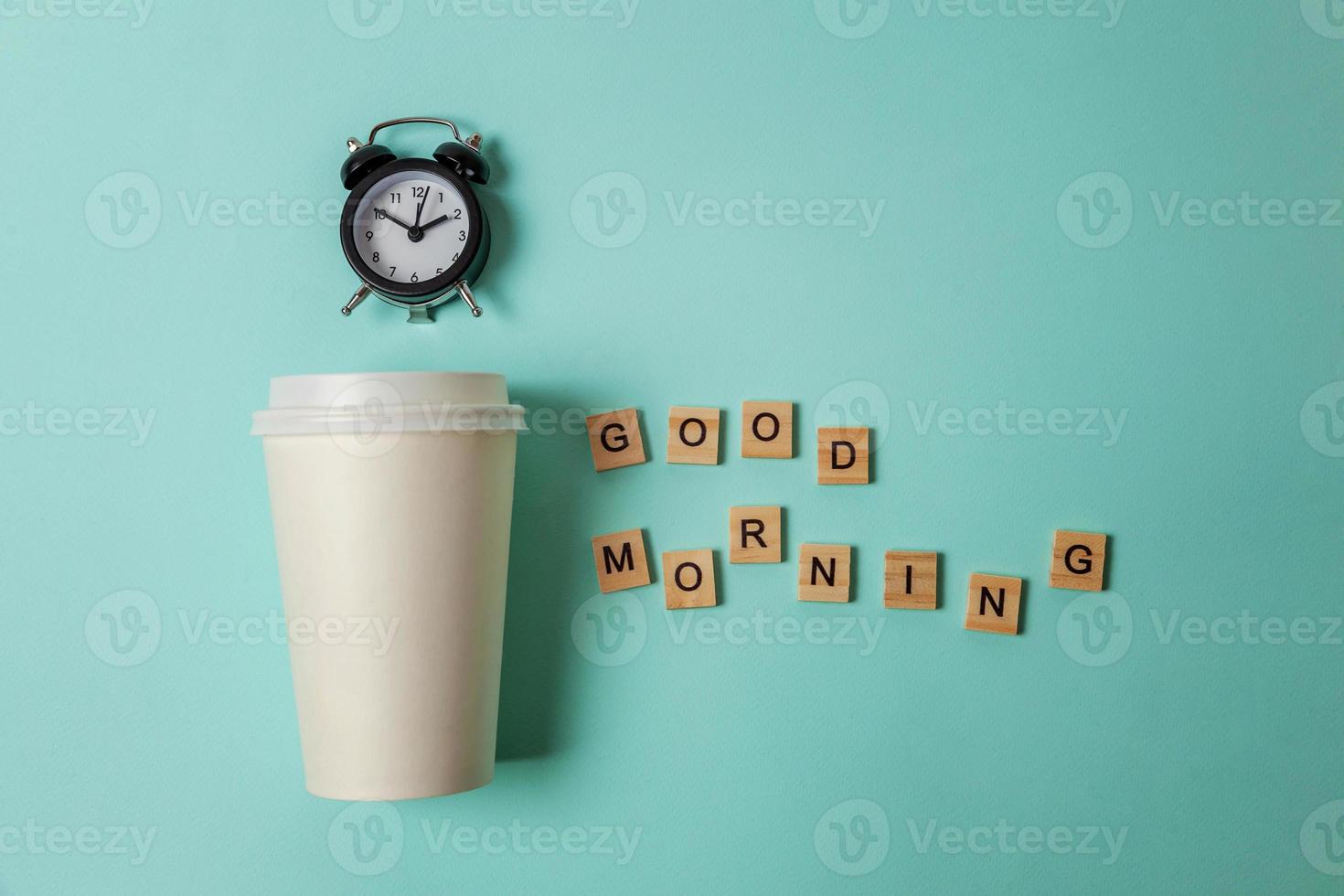 Einfach flach Design Papierkaffeetasse und Wecker auf blauem, pastellfarbenem, trendigem Hintergrund. Getränk zum Mitnehmen und Frühstücksgetränk. guten morgen aufwachen wach konzept. Kopierbereich von oben. foto