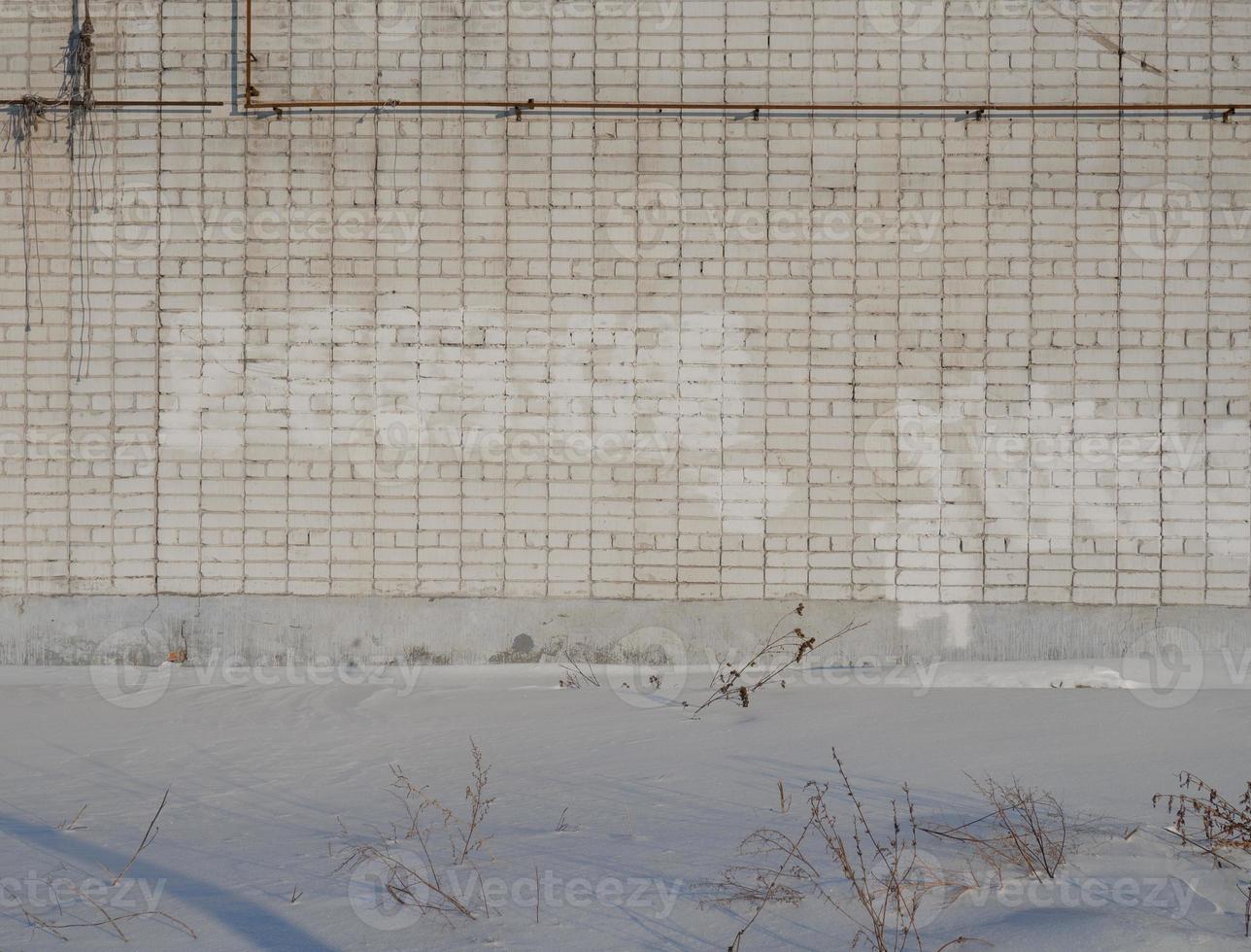 weiße Backsteinmauer und Schnee. Winter in der Stadt. foto