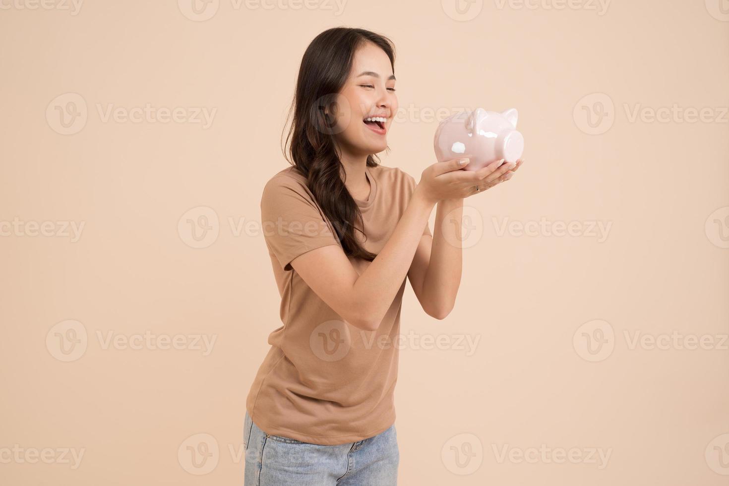 glückliche junge frau, die sparschwein hält, das im studio steht foto