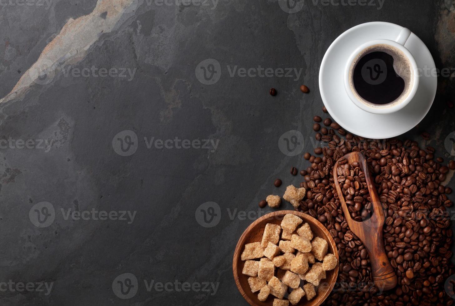 Kaffeetasse, Bohnen und brauner Zucker auf Steintisch foto