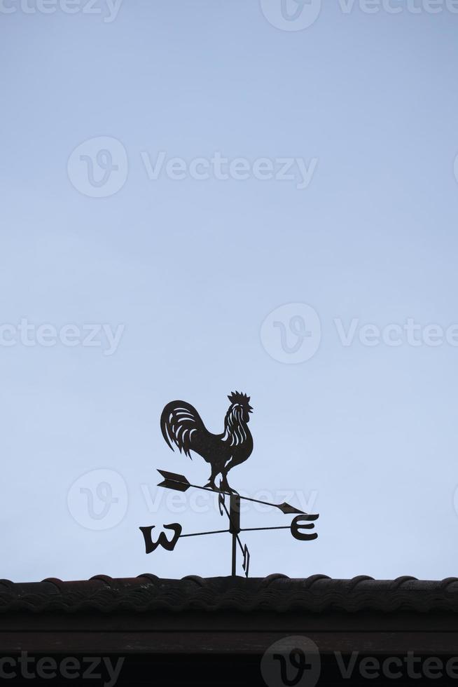 Die alte Windfahne mit einem Hahnsymbol auf dem Dach, traditionelle Technologieausrüstung zur Vorhersage und Messung des Windwetters in der Luft, Vintage-Dekoration, Windrichtungsinstrument. foto