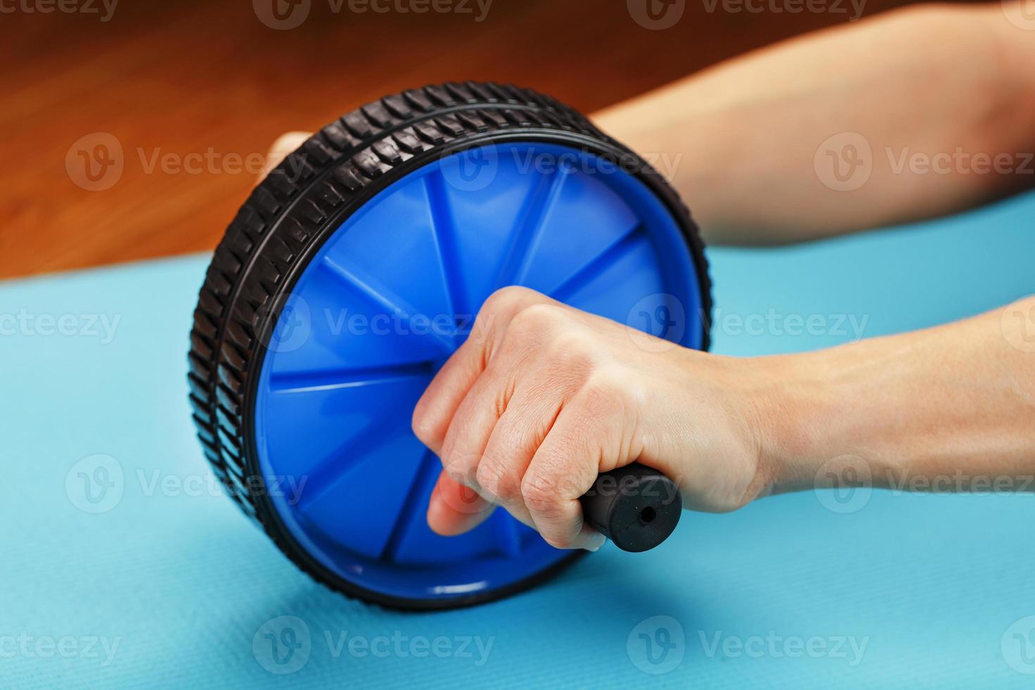 Rolle zum Training der Presse in den Händen auf einem blauen Teppich. foto