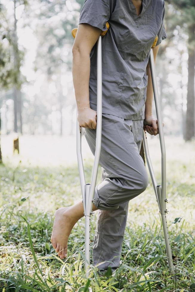 junge asiatische physiotherapeutin, die mit einer älteren frau beim gehen mit einer gehhilfe arbeitet foto