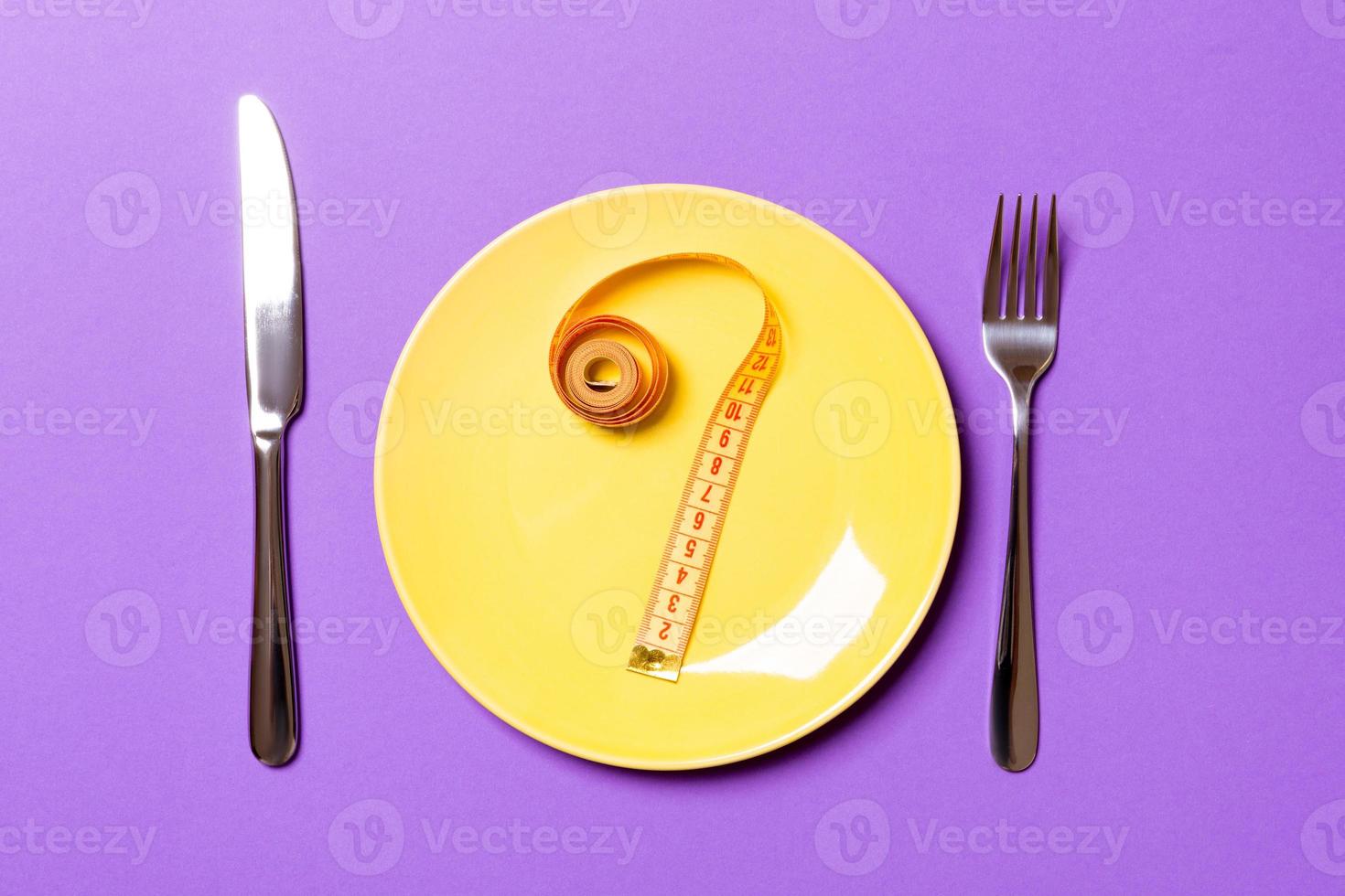 Fragezeichen aus Maßband auf runder Platte auf violettem Hintergrund. Draufsicht auf Zögern und Diätkonzept foto