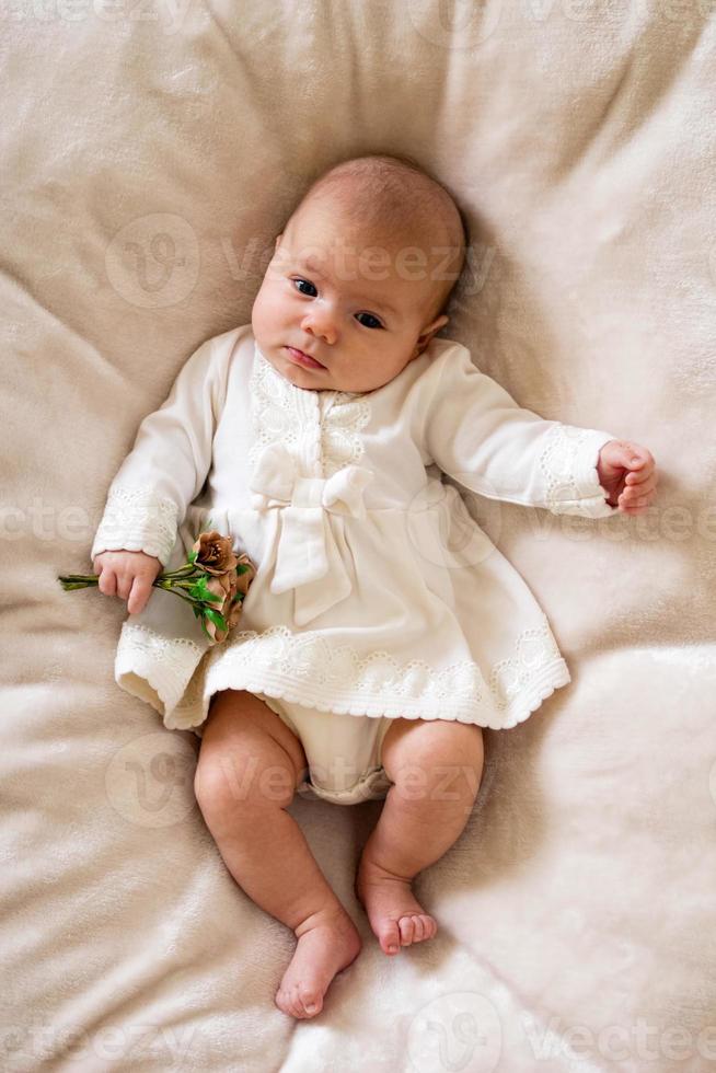 süßes kleines Mädchen im weißen Kleid mit Blumenstrauß in der Hand. foto