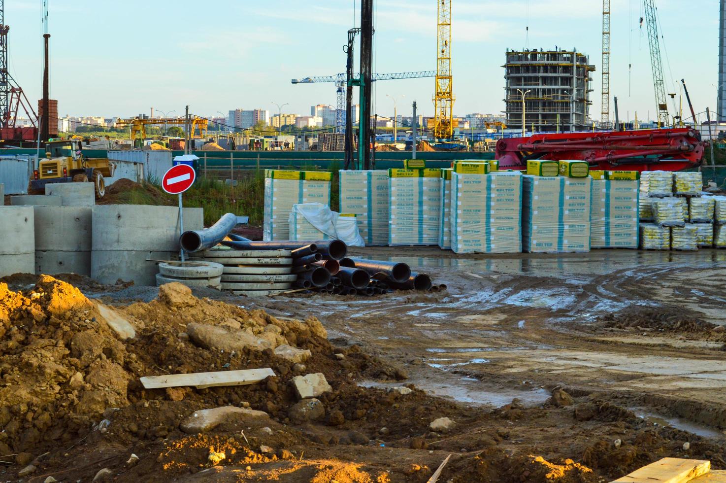 Baustelle in der Innenstadt. stürzte das Stoppschild herunter. Baumaterialien werden in einem Haufen unter der Folie gestapelt. in der ferne wird ein haus gebaut, da steht ein baukran foto