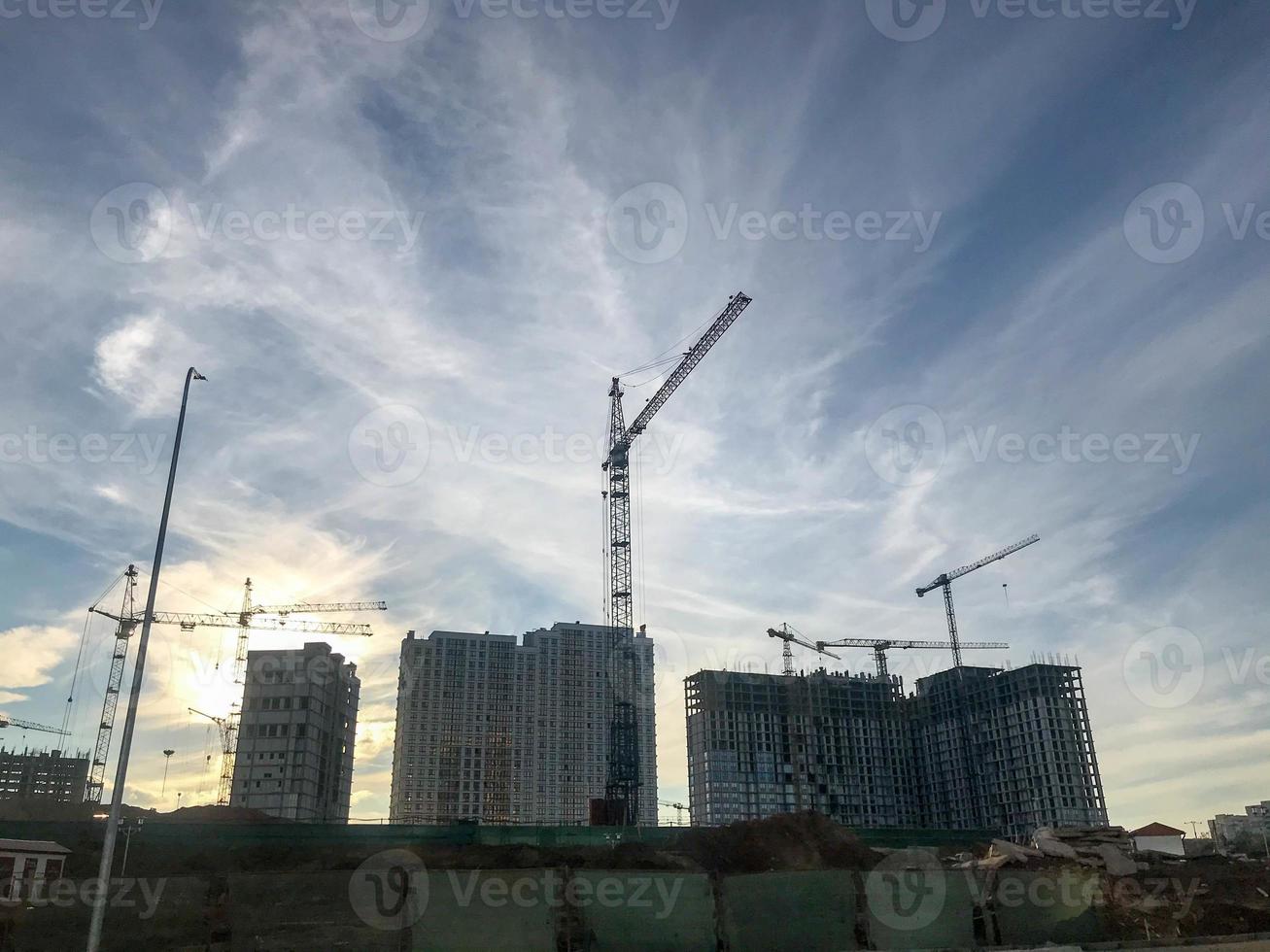 Stadtlandschaft, Bau eines neuen Stadtviertels. Baukräne, Betonblockhäuser. Bau eines multifunktionalen Komplexes. sonniger und klarer Tag foto