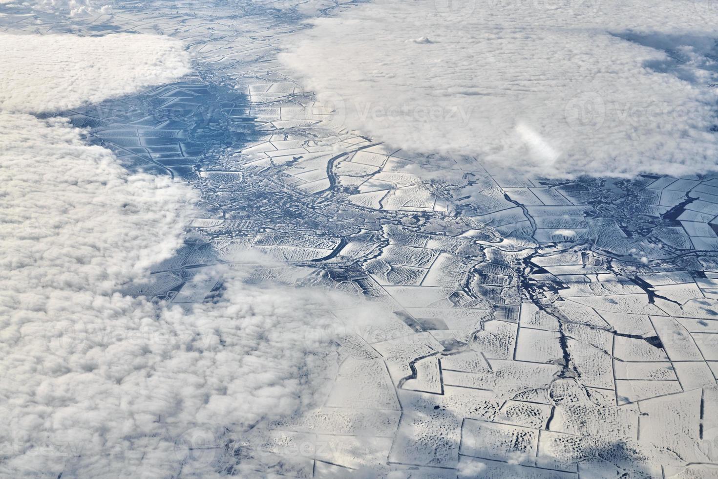 luftwolkengebilde blick über die wolkenspitze zu schneebedeckten flüssen, straßen, städten und feldern, winterluft foto