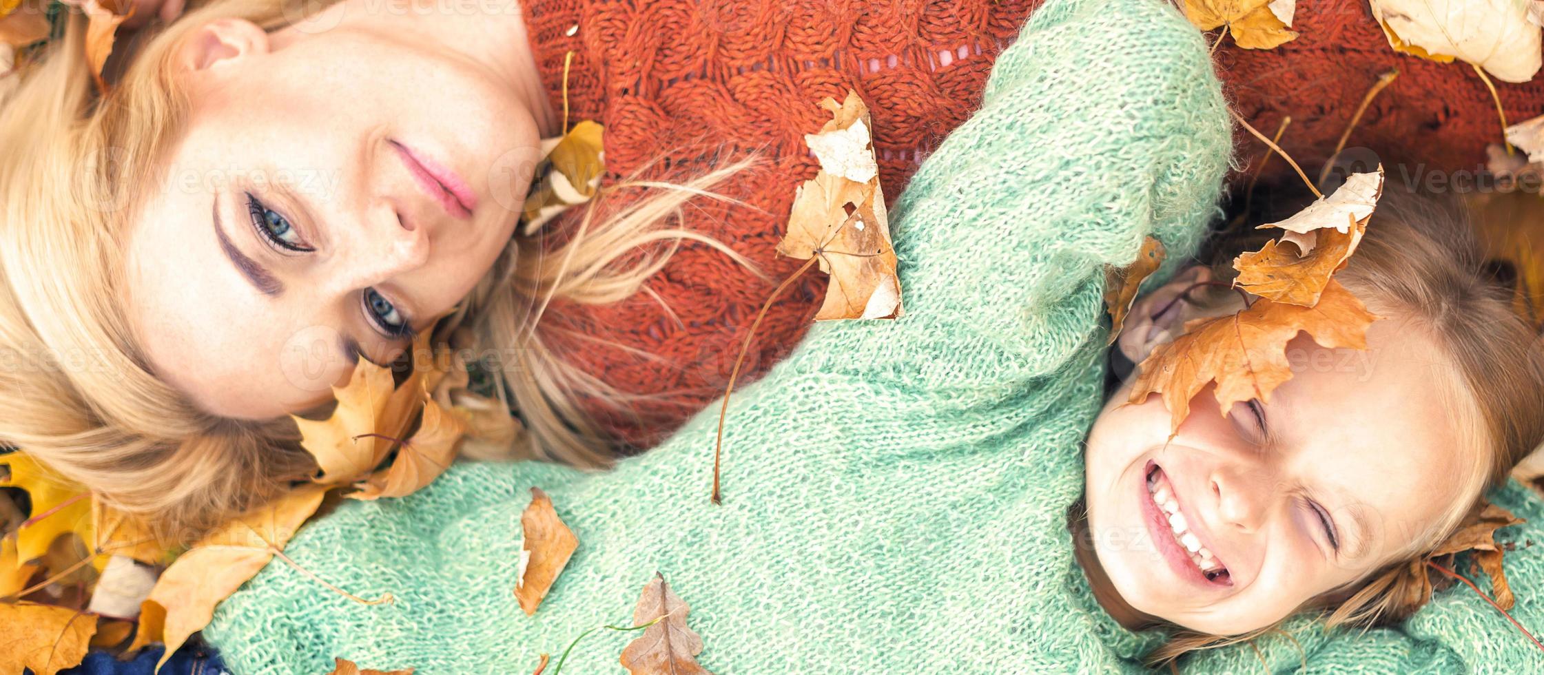 Mädchen und Mutter liegen auf Herbstlaub foto