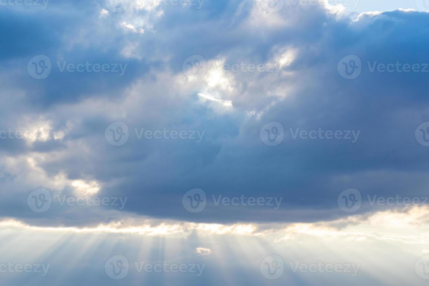 Lichtstrahlen, die durch die Regenwolken scheinen. Licht, das vom Himmel an den grauen Wolken vorbei scheint. foto