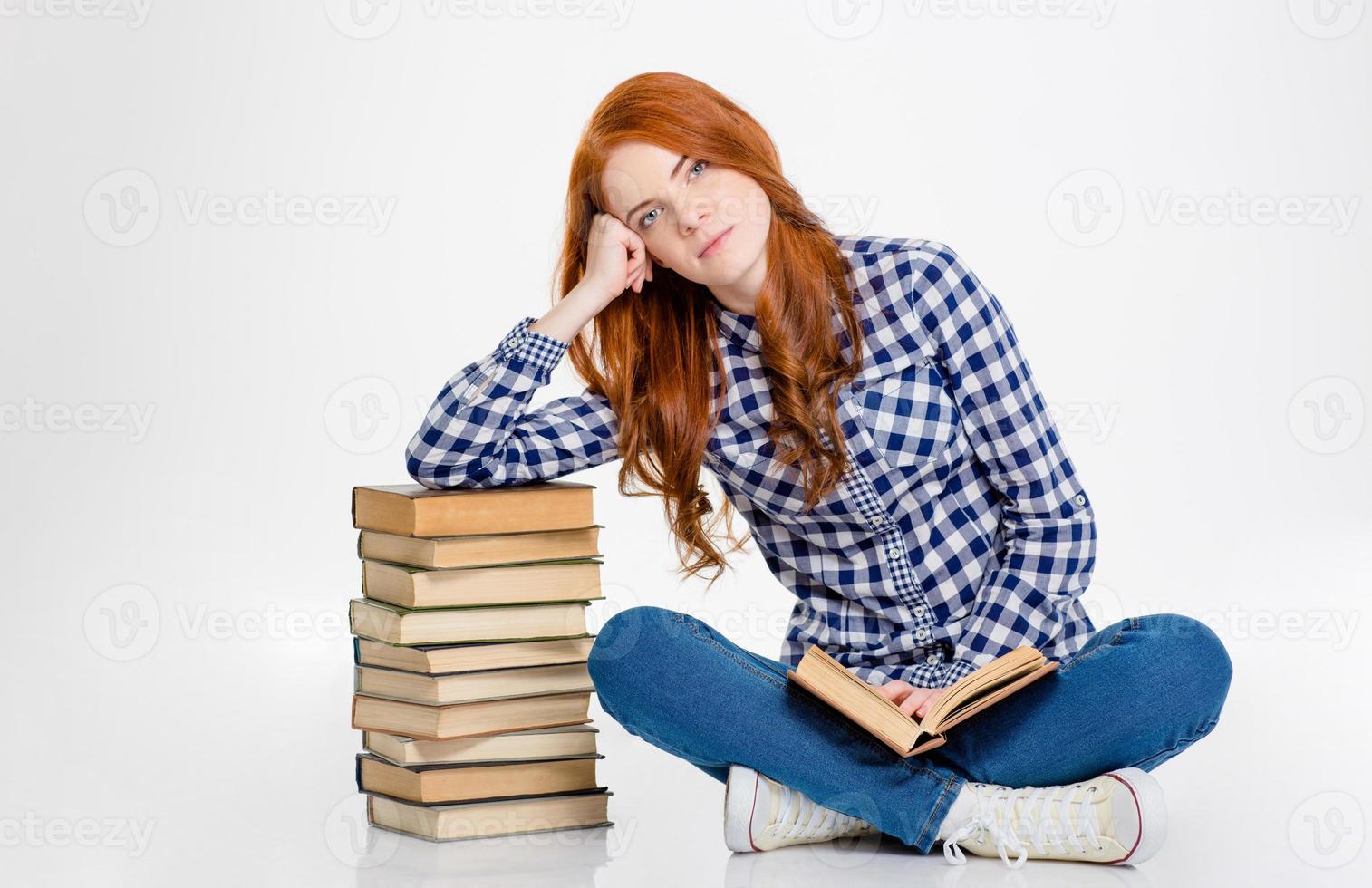 thoghtful Mädchen sitzt und stützt sich auf Stapel der Bücher foto