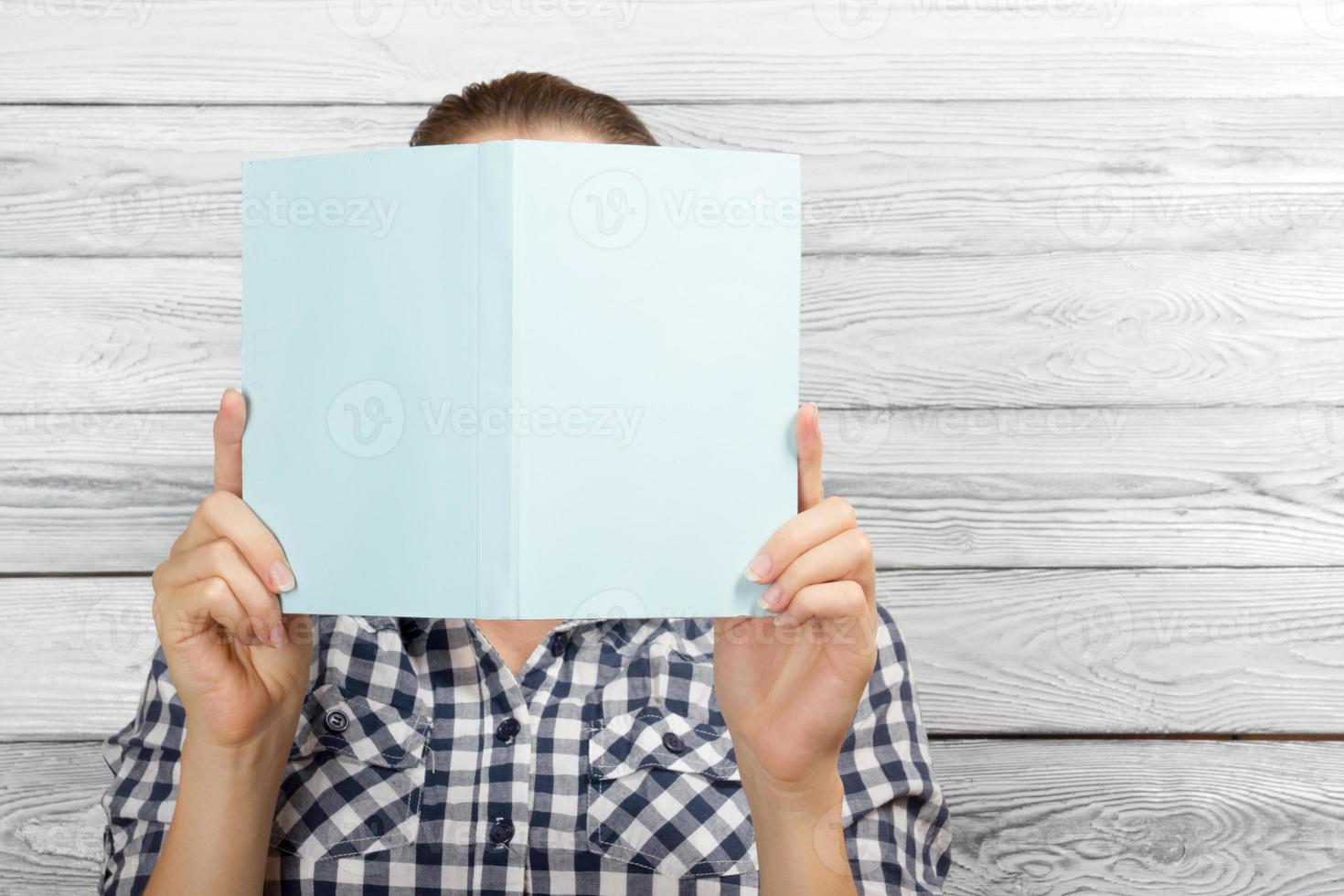 Frau liest ein Buch und bedeckt ihr Gesicht foto