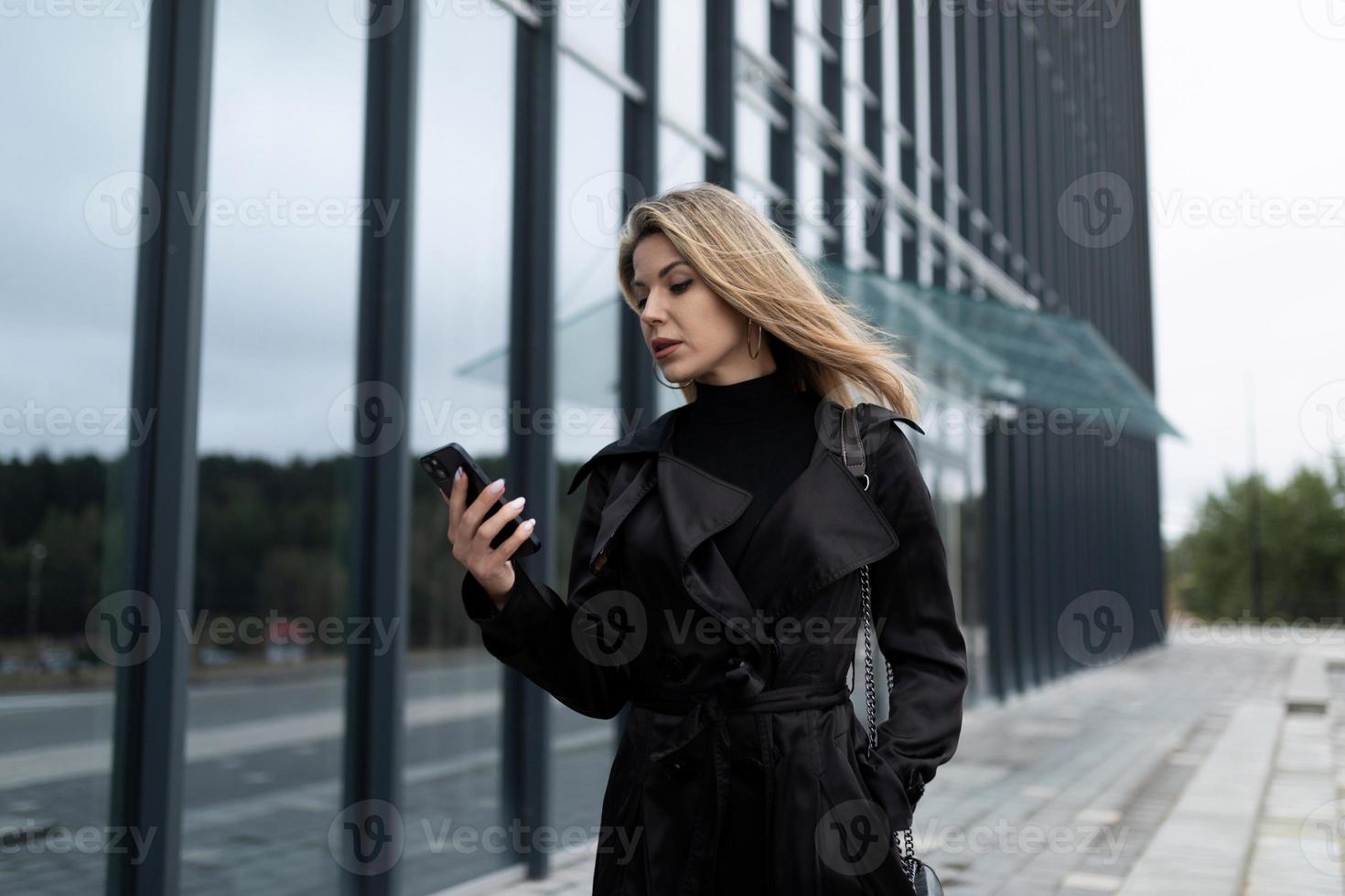 erfolgreiche geschäftsfrau mittleren alters, die auf dem weg zur arbeit auf das telefon schaut foto