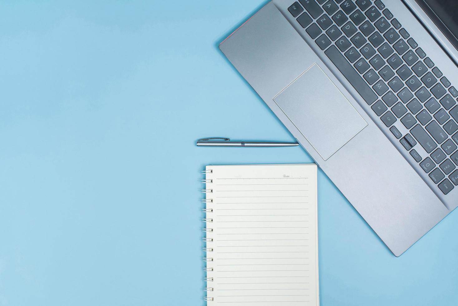 Draufsicht der Bürotischplatte mit Laptop-Computer, Stift und Notizbuch mit Platz foto