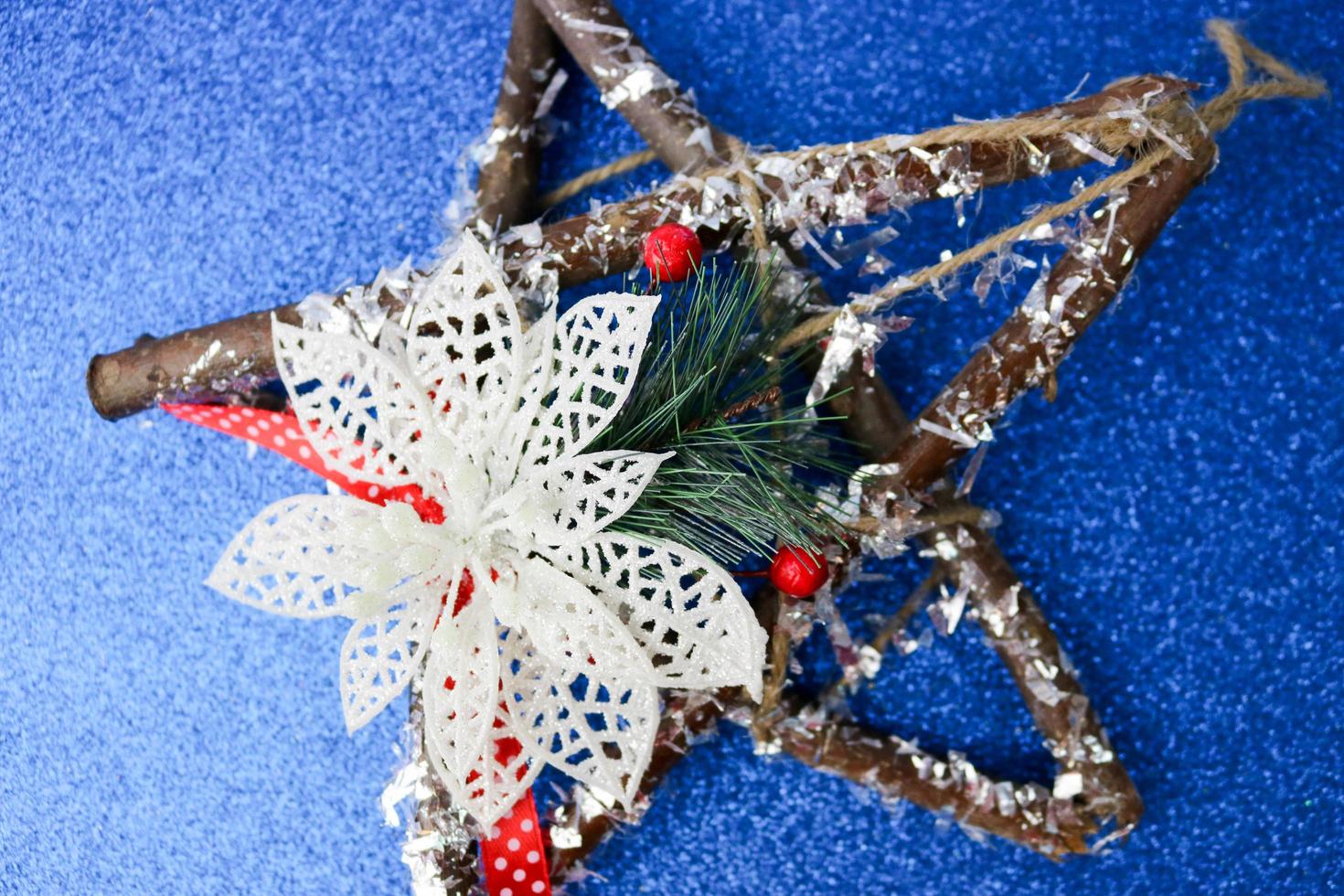 großer dekorativer schöner weihnachtsstern aus holz, ein selbstgemachter adventskranz aus tannenzweigen und stöcken auf dem festlichen neuen jahr glücklich blau glänzender fröhlicher hintergrund. Feiertagsdekorationen foto