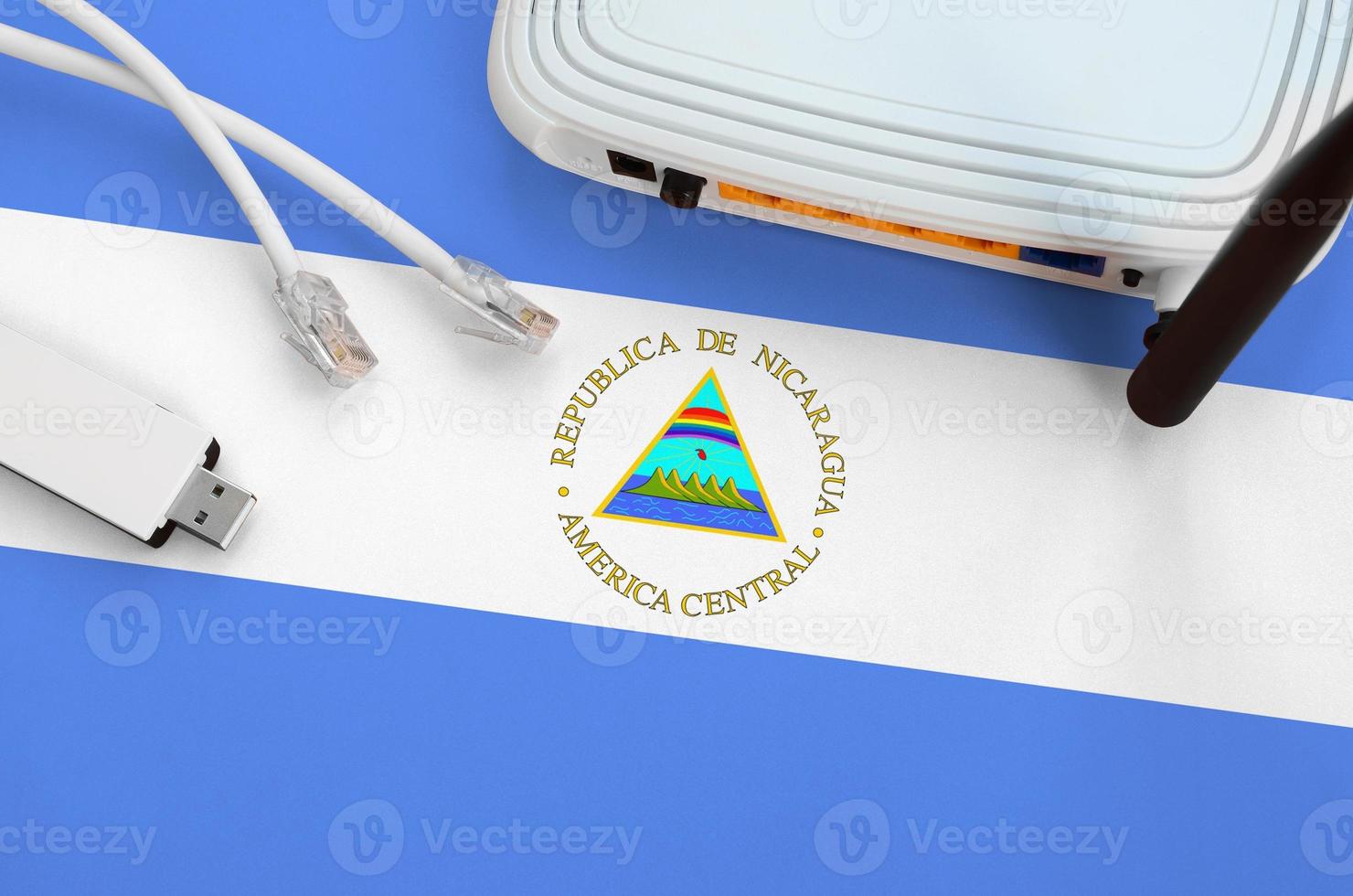 nicaragua-flagge auf tisch mit internet-rj45-kabel, drahtlosem usb-wlan-adapter und router. Konzept der Internetverbindung foto