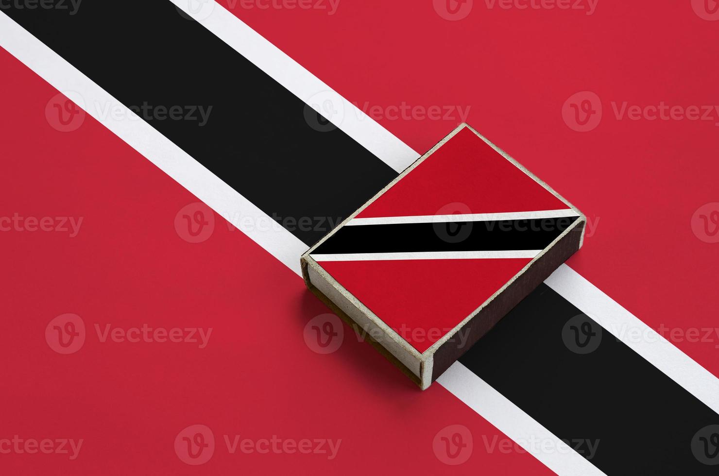 die flagge von trinidad und tobago ist auf einer streichholzschachtel abgebildet, die auf einer großen flagge liegt foto