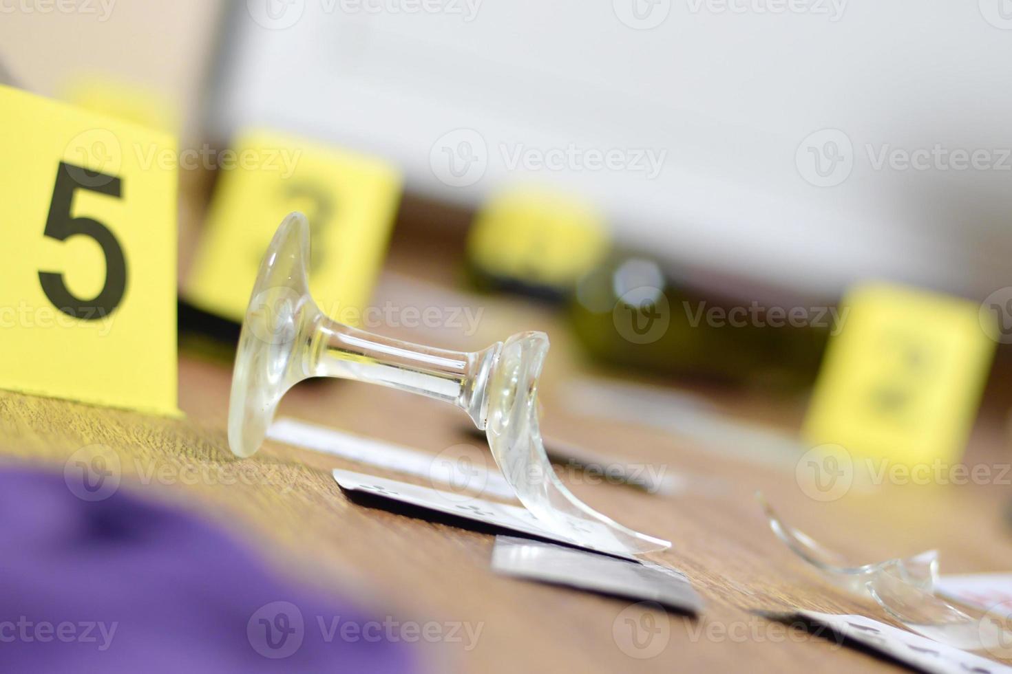 zerbrochenes Glas und eine Flasche Wein, die während der Ermittlungen am Tatort als Beweismittel markiert wurden. viele gelbe Markierungen mit Zahlen foto