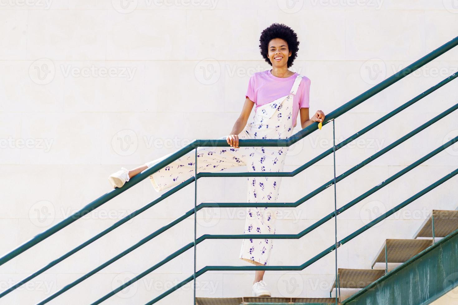 Fröhliche schwarze Frau, die auf der Treppe steht foto