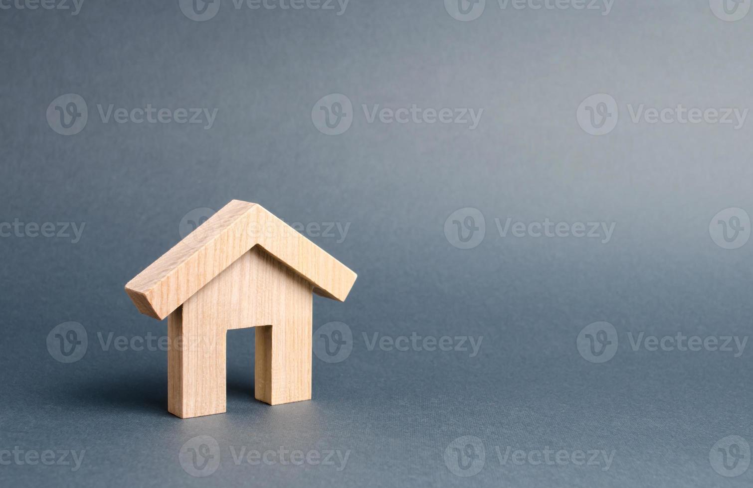 kleines Wohnhaus aus Holz auf grauem Hintergrund. Hypothek und Kredit für den Kauf. Minimalismus. immobilienkonzept, kauf von bezahlbarem wohnraum, immobilienvermietung. Vermögenssteuer. foto