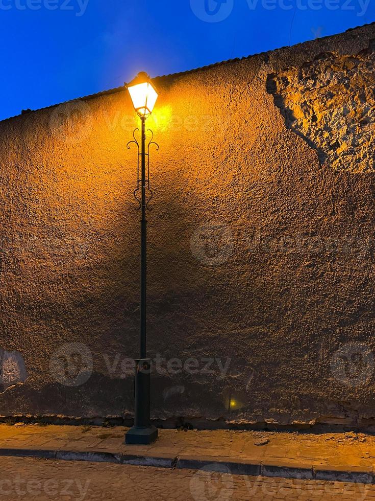 Straßenlaterne im Retro-Stil neben einer alten Mauer in der Dämmerung. foto