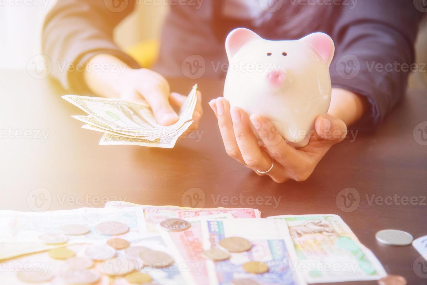 Sparschwein in der Hand mit Bargeldhaufen. foto