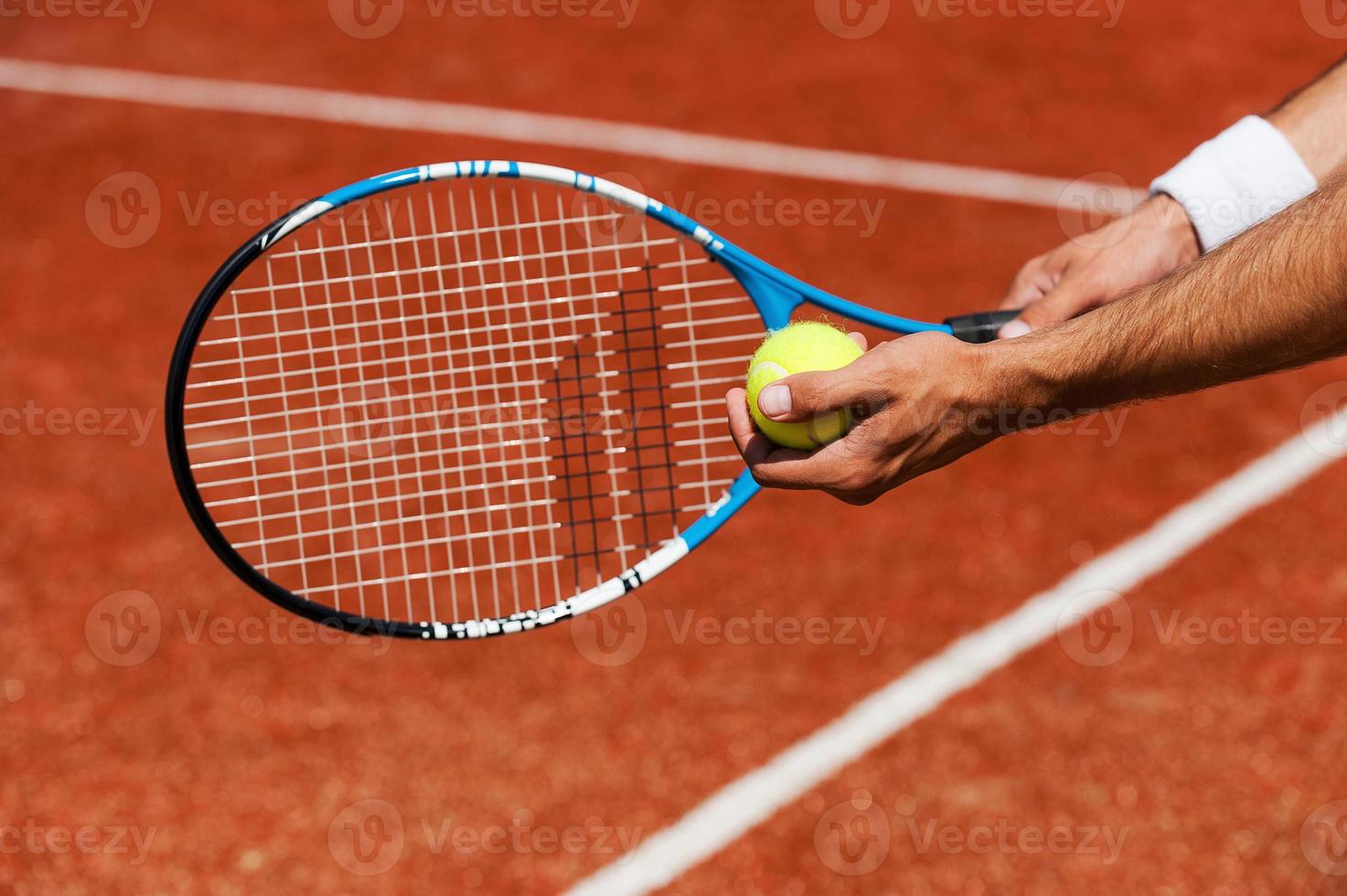 dienender Ball. Nahaufnahme eines männlichen Tennisspielers, der Ball serviert foto