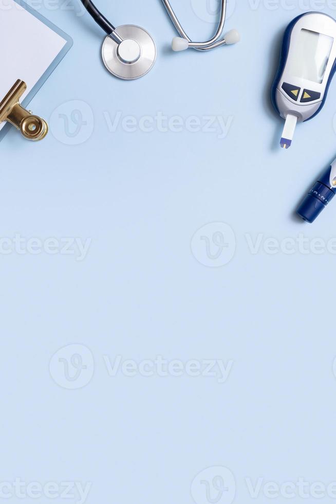 Blutzuckermessgerät, Lanzette, Test und Stethoskop auf blauem Hintergrund mit Kopierraum. Ansicht von oben, flach liegend foto