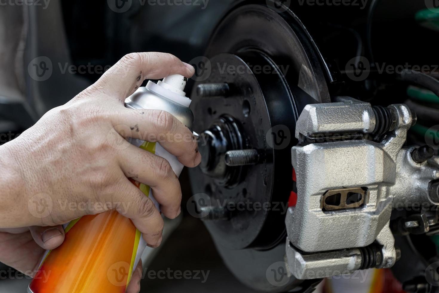 Geben Sie einem Mann Sprühfarbe Reparaturscheibe Bremsplatte des Autosattels für Rostschutz foto