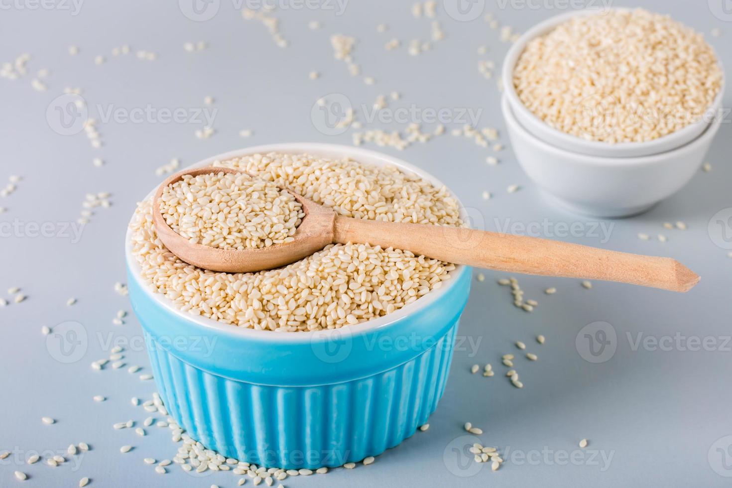 Holzlöffel mit Sesam in einer Schüssel mit Sesam auf grauem Hintergrund. vitamin ernährung. foto