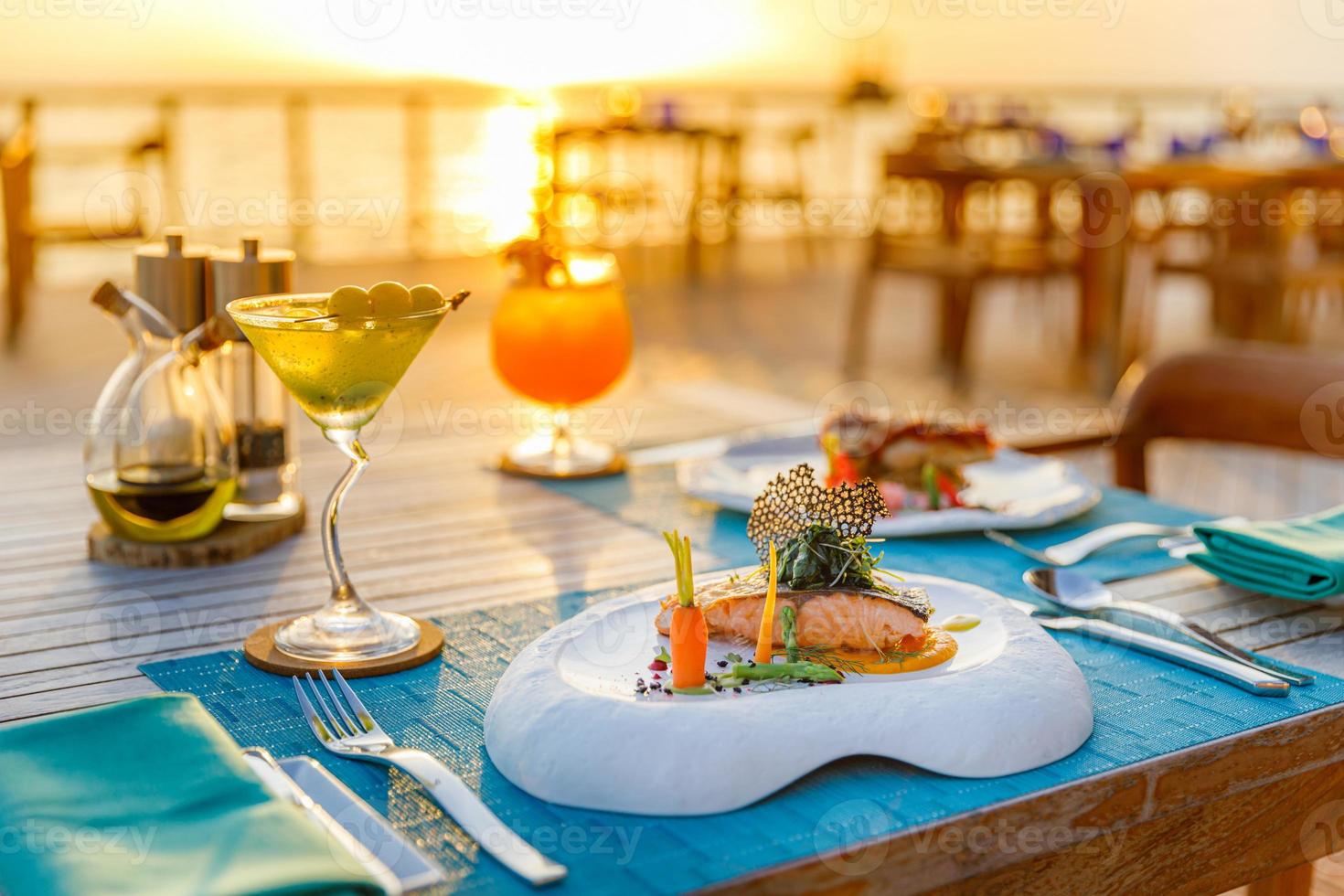 erstaunliche romantische Tische im Strandrestaurant im Freien. Holzdeck mit Kerzen unter Sonnenuntergang. Urlaub, Flitterwochen, romantische Liebe, Luxus-Dinner, exotische Tischdekoration mit Meerblick foto