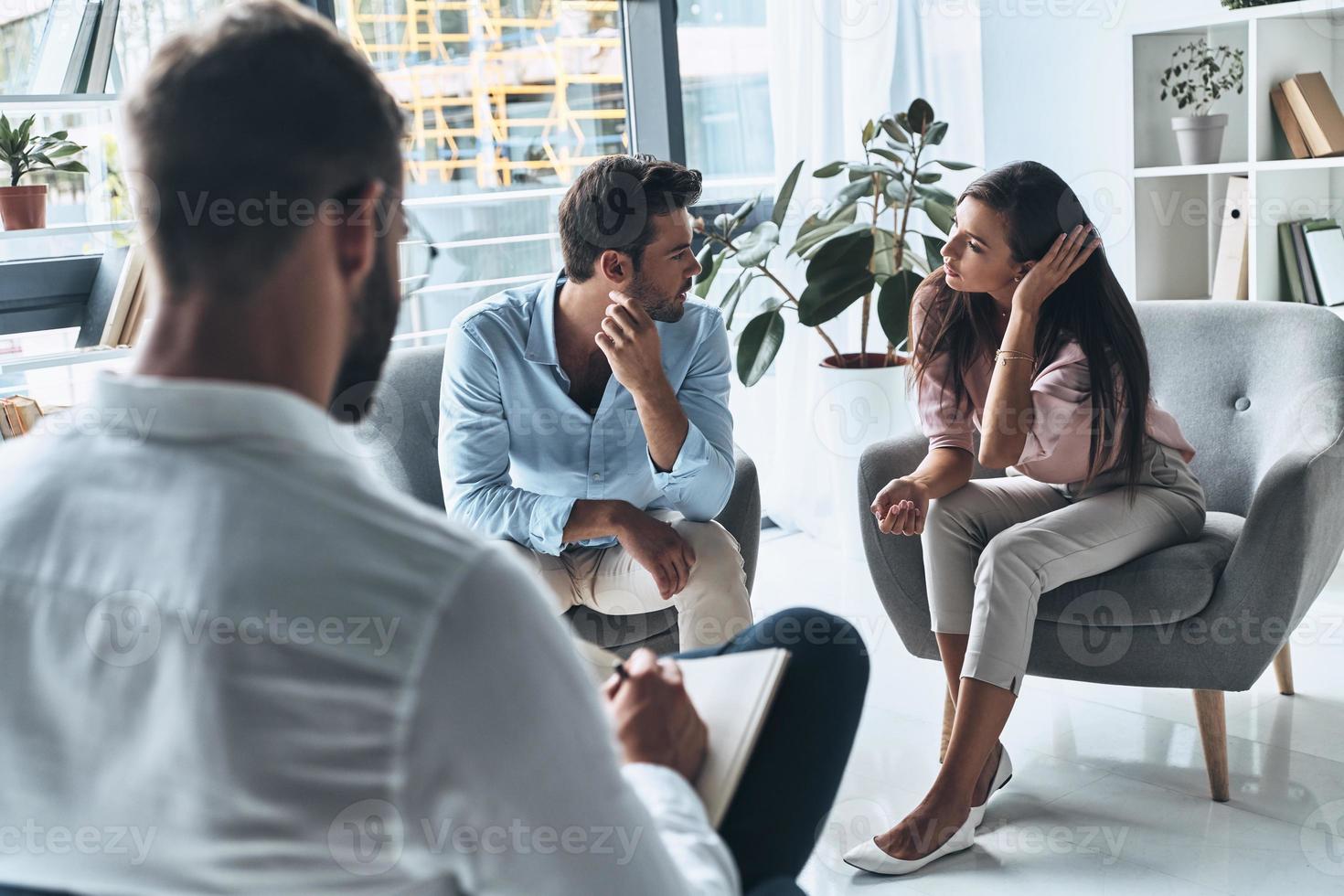 Paar im Konflikt. junges Ehepaar spricht, während es auf der Therapiesitzung mit dem Psychologen sitzt foto