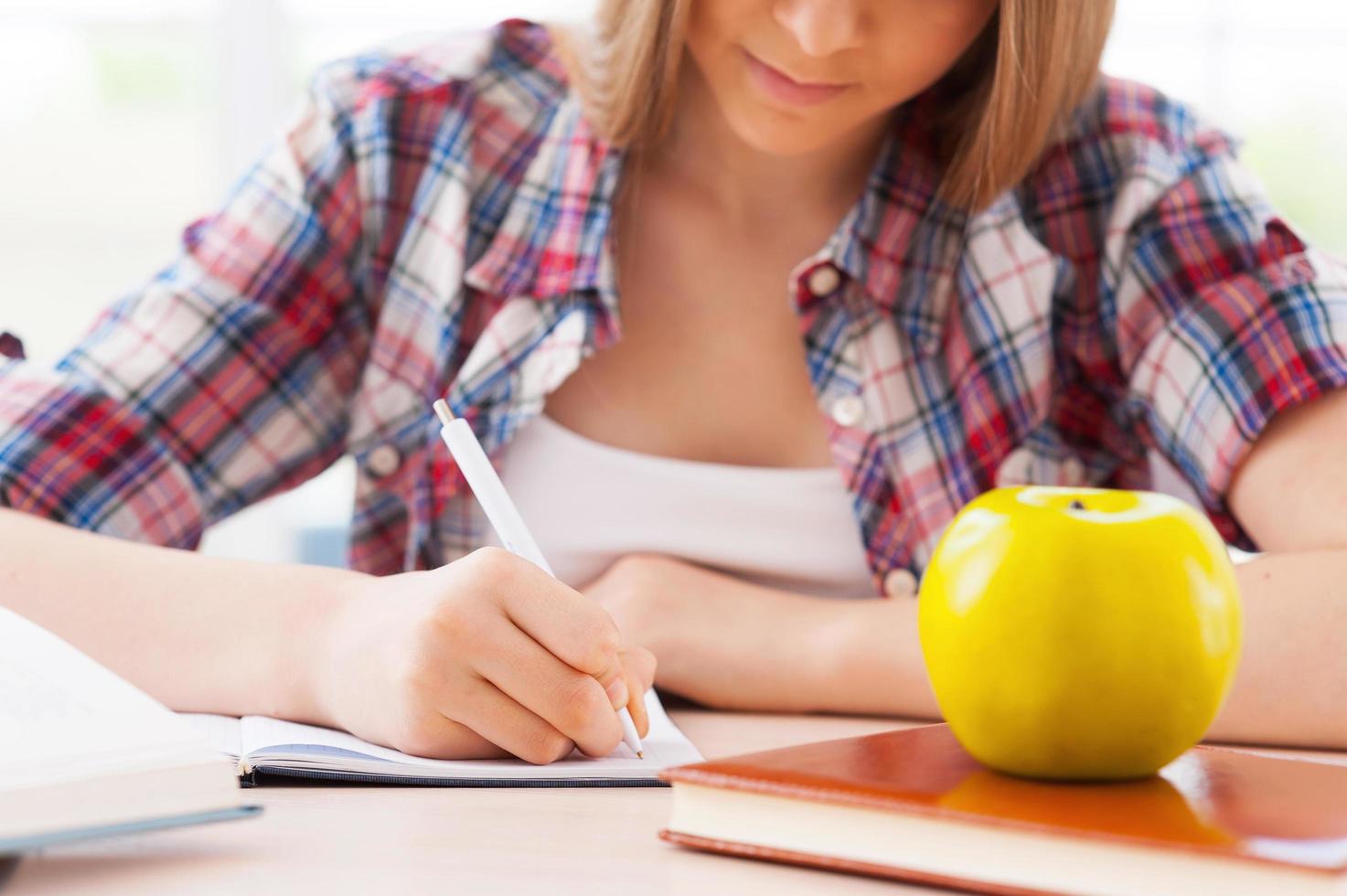 Vorbereitung auf Prüfungen. Zugeschnittenes Bild eines selbstbewussten Teenager-Mädchens, das beim Sitzen am Schreibtisch studiert foto