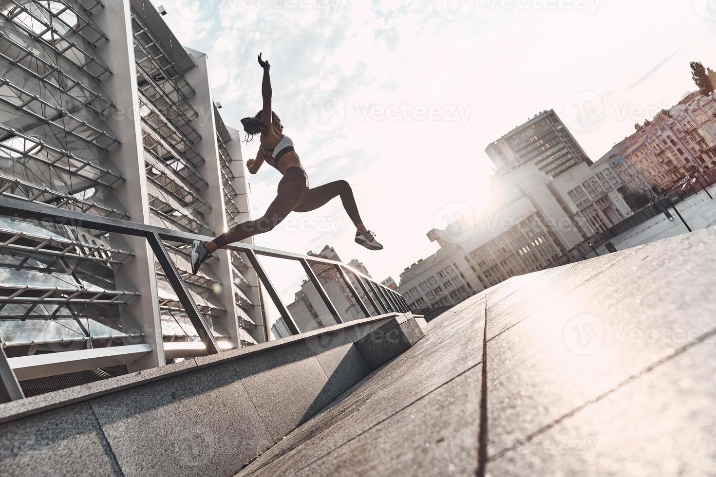 nur fliegen. in voller Länge von der modernen jungen Frau in der Sportkleidung, die beim Trainieren im Freien springt foto