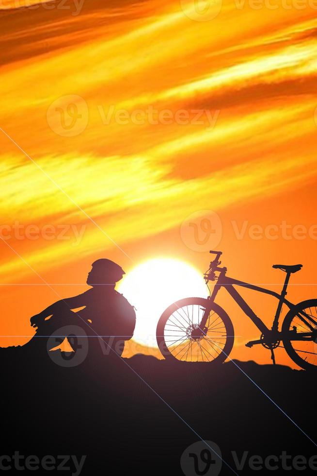 eine Silhouette eines Radfahrers, der abends vom Berg absteigt. foto