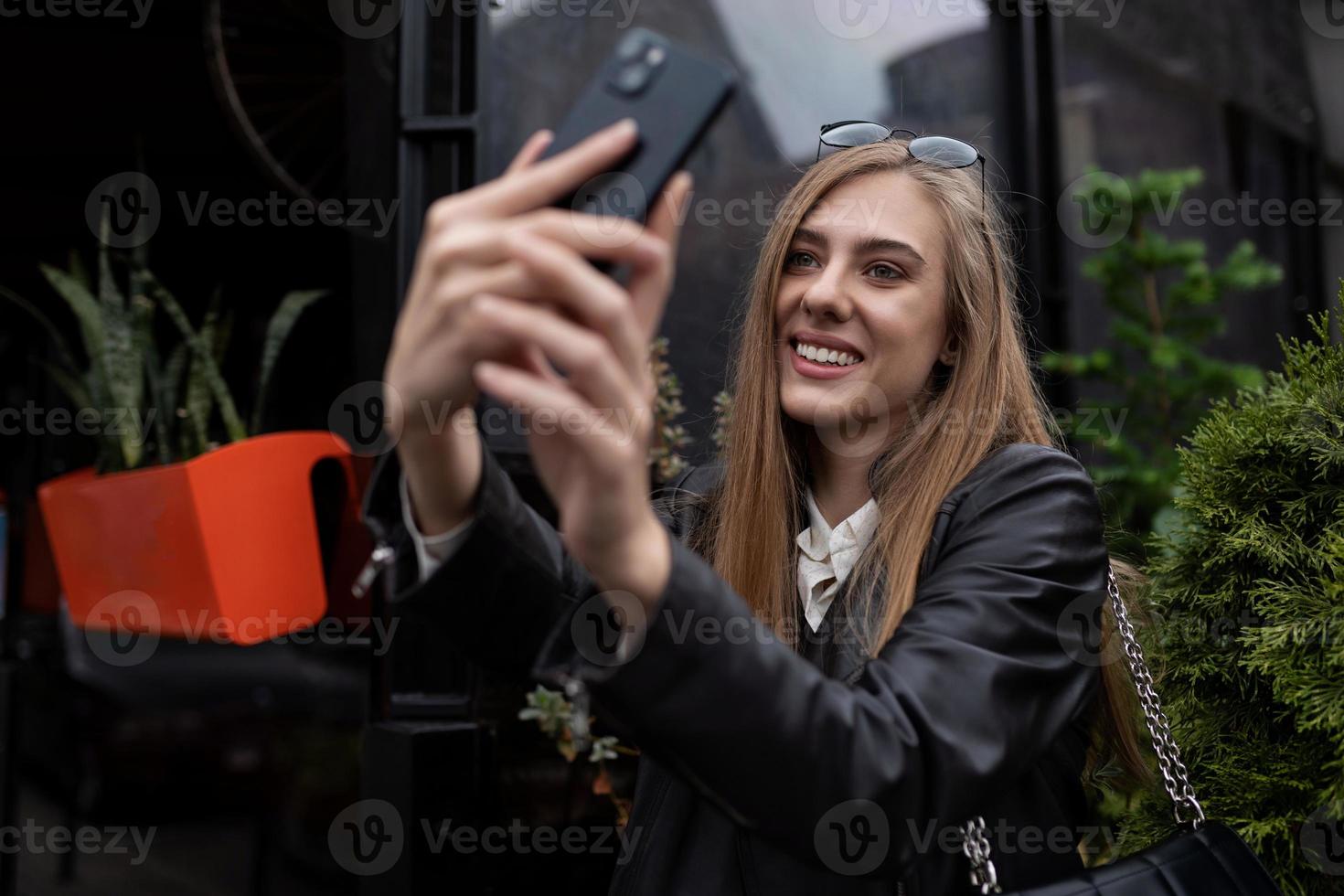 junge bloggerin macht ein selfie neben einem beliebten café in der stadt foto