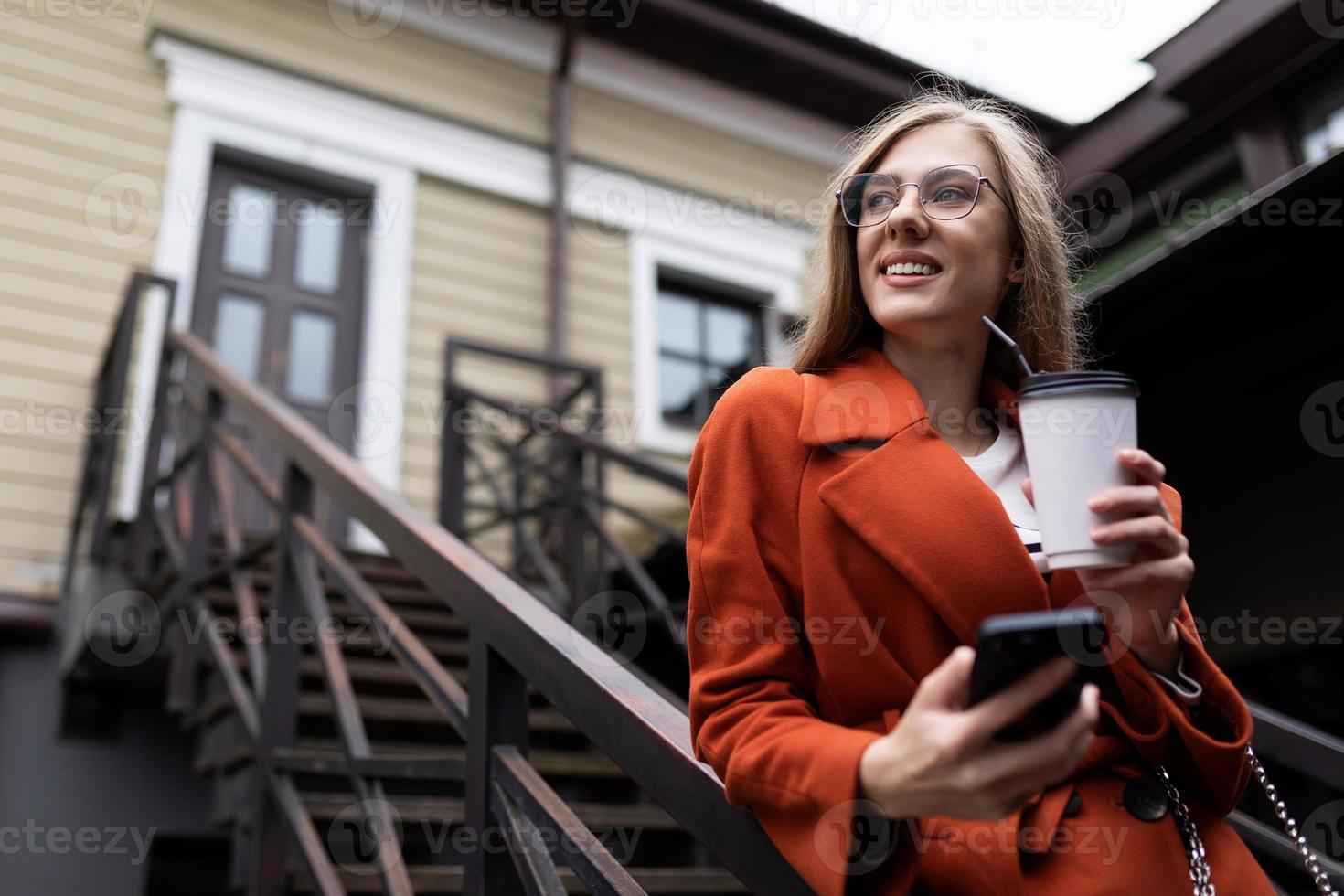 Porträt einer erfolgreichen jungen Geschäftsfrau mit einer Tasse Kaffee von einem Mobiltelefon in ihren Händen, Online-Banking-Konzept foto