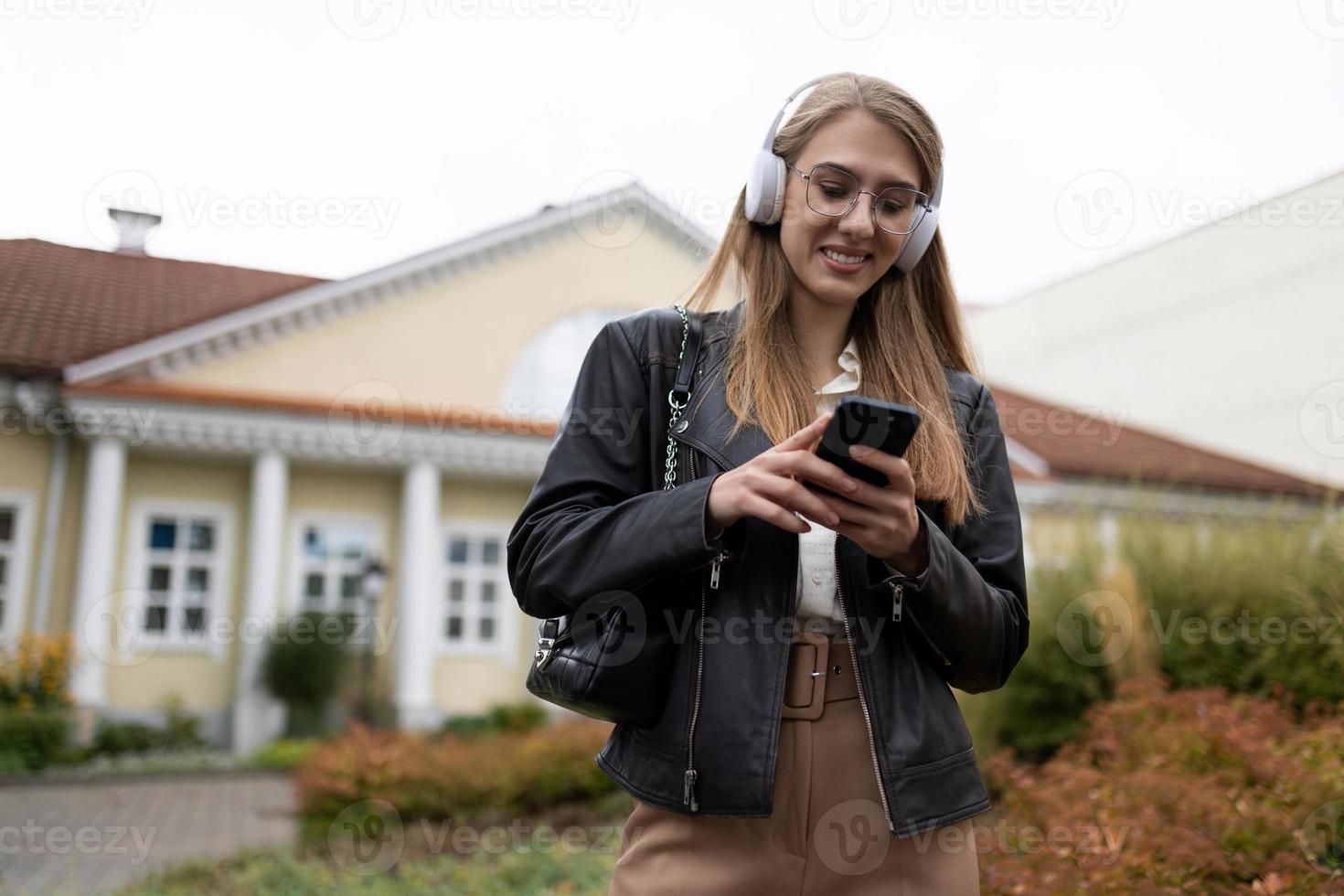 junge frau geht zur arbeit und hört musik über kopfhörer per handy foto