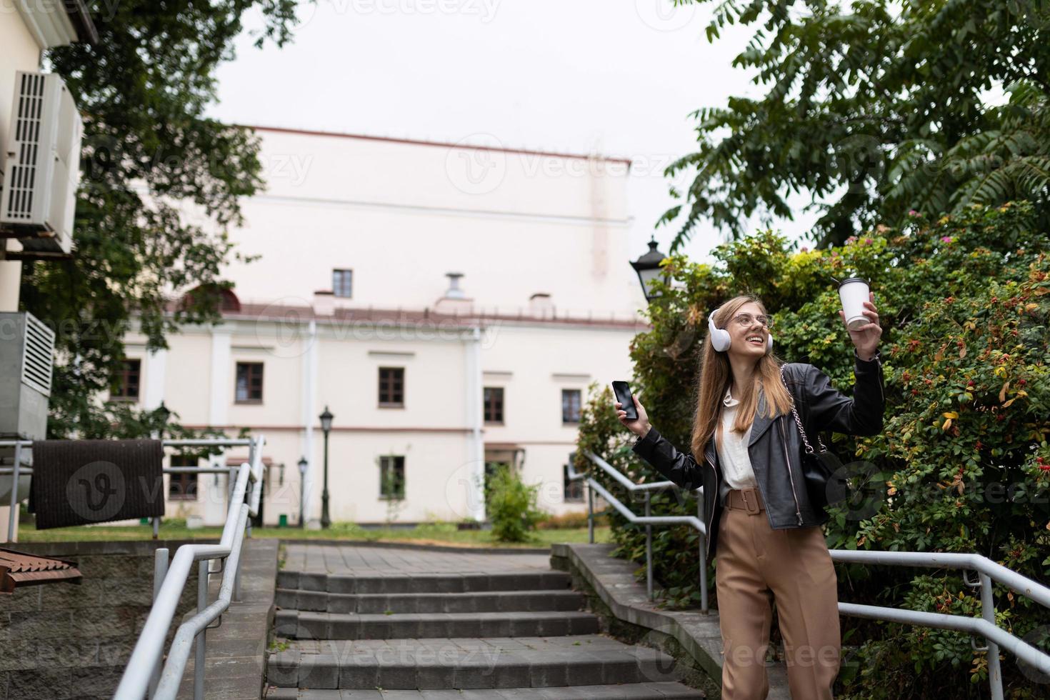 eine junge frau tanzt mit kopfhörern vor dem hintergrund der urbanen umgebung, ohne schüchtern zu sein foto