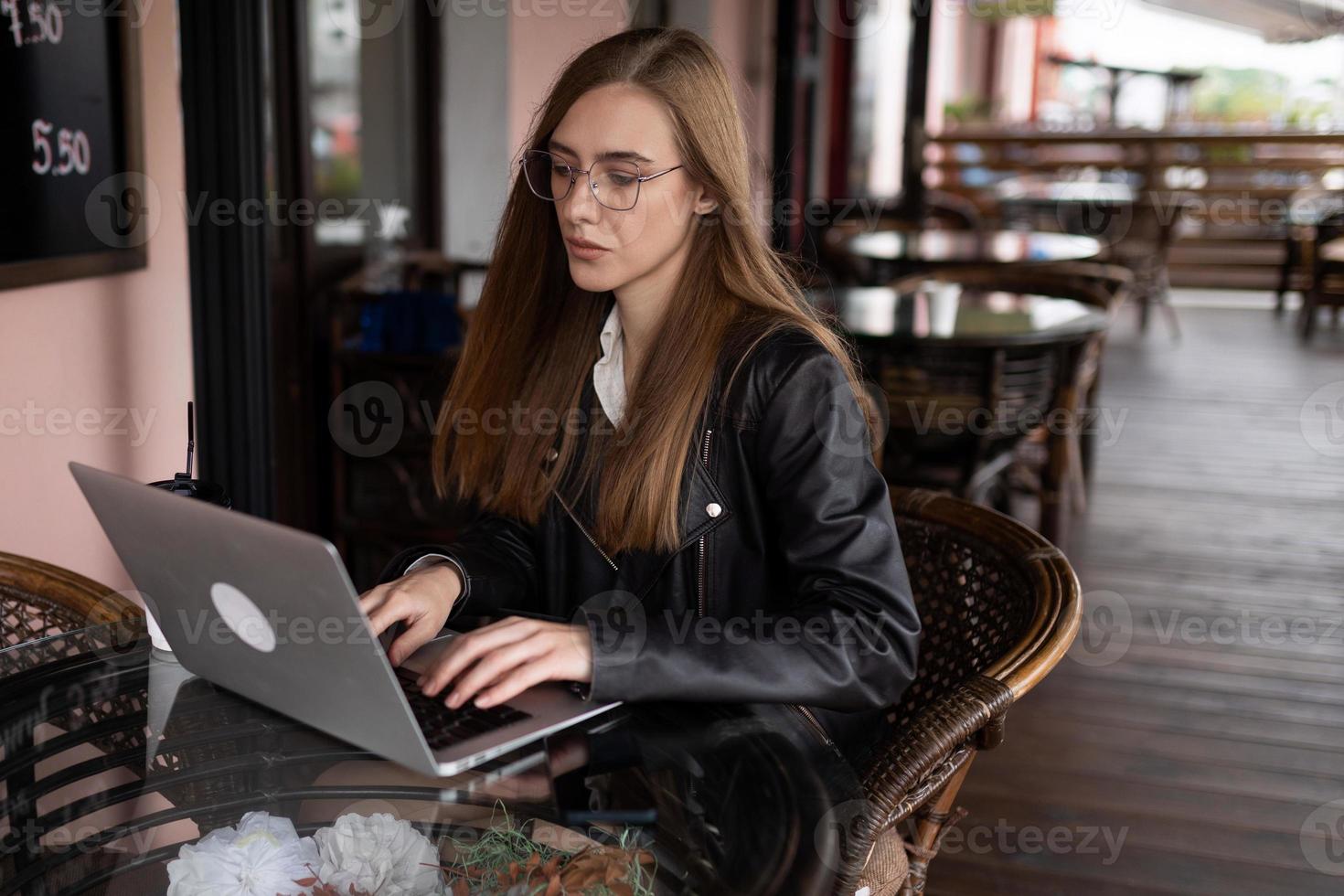 junge Frau, die an einem Laptop in einem Stadtcafé arbeitet foto