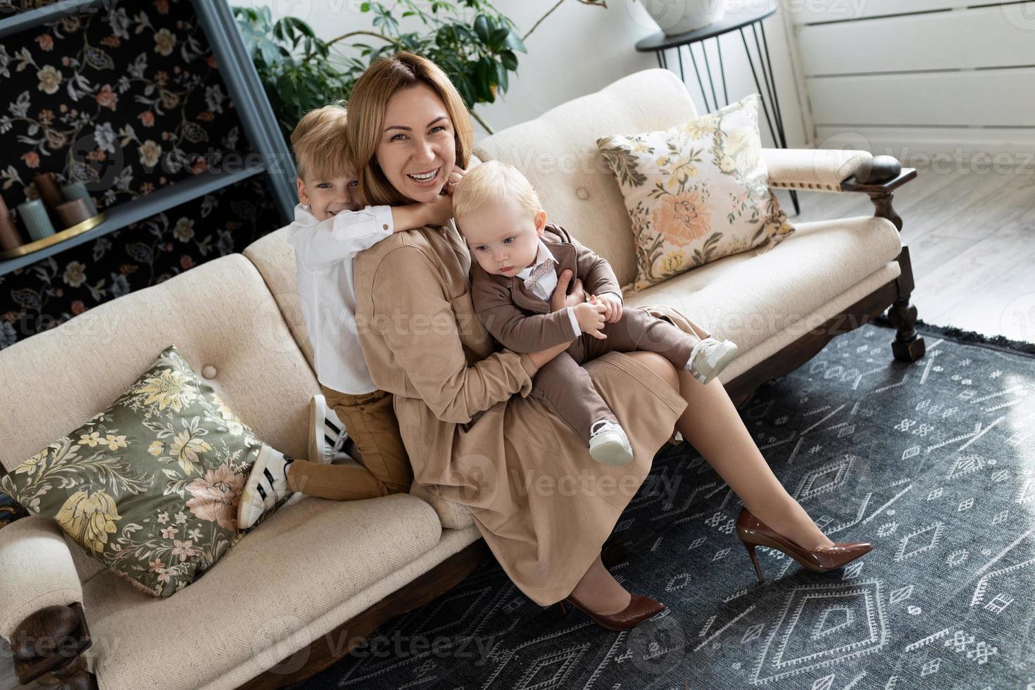 glückliche mutter, die mit zwei jungen söhnen herumalbert, die auf dem sofa sitzen foto