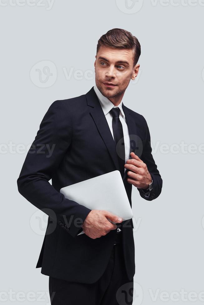 sich um das Geschäft kümmern. hübscher junger Mann mit digitalem Tablet im Stehen vor grauem Hintergrund foto